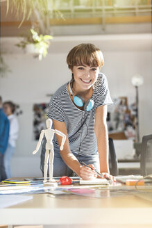 Porträt lächelnd weibliche Design-Profi mit Künstler Figur Skizzieren im Büro - CAIF09240