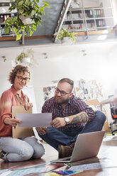 Designprofis besprechen Korrekturabzüge am Laptop im Büro - CAIF09279