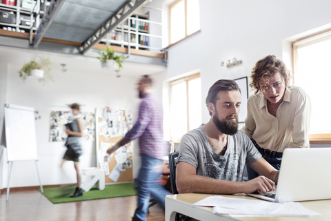 Design-Profis arbeiten am Laptop im Büro, lizenzfreies Stockfoto