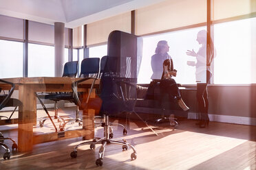 Businesswomen talking at window in sunny conference room - CAIF09291