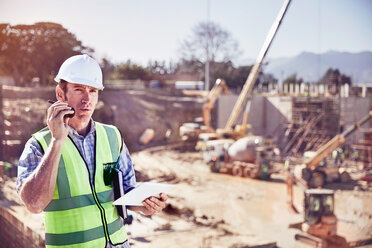 Bauarbeiter Vorarbeiter im Gespräch über Walkie-Talkie auf sonniger Baustelle - CAIF09311