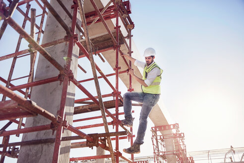 Ein Bauarbeiter klettert auf einer sonnigen Baustelle auf einen Betonstahl - CAIF09312