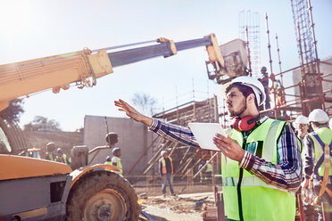 Bauführer mit digitalem Tablet, das die Ausrüstung auf einer sonnigen Baustelle steuert - CAIF09315