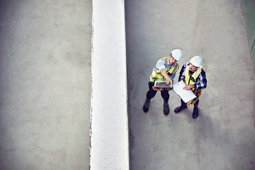 Bauarbeiter und Ingenieur mit Laptop im Gespräch auf der Baustelle - CAIF09316