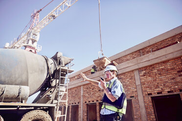 Bauarbeiter-Vorarbeiter mit Walkie-Talkie auf einer sonnigen Baustelle - CAIF09320
