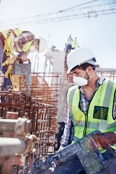 Construction worker wearing protective mask at sunny construction site - CAIF09322