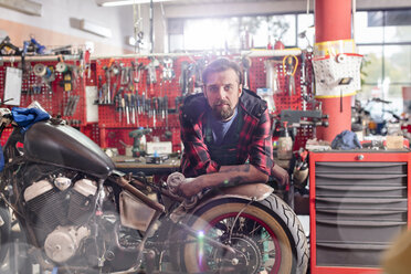 Porträt eines seriösen, selbstbewussten Motorradmechanikers in der Werkstatt - CAIF09343
