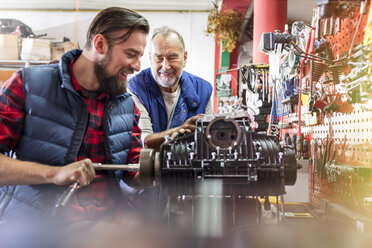 Männliche Motorradmechaniker reparieren den Motor in der Werkstatt - CAIF09365
