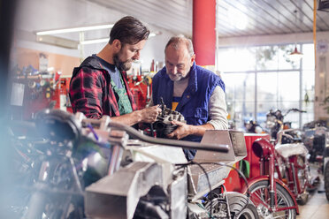 Männliche Motorradmechaniker reparieren ein Teil in der Werkstatt - CAIF09367