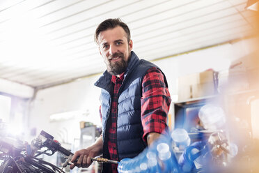 Portrait confident male motorcycle mechanic working in workshop - CAIF09368