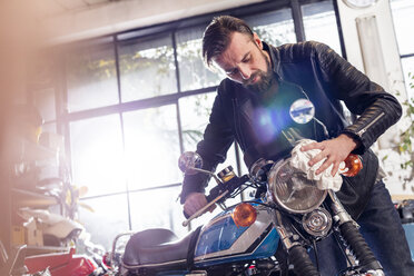 Männlicher Motorradmechaniker beim Abwischen des Motorrads in der Werkstatt - CAIF09372