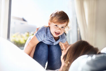 Portrait smiling baby boy on mother’s knees - CAIF09375