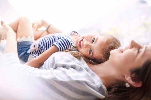 Porträt lächelnde Tochter, die auf der Mutter liegt - CAIF09380