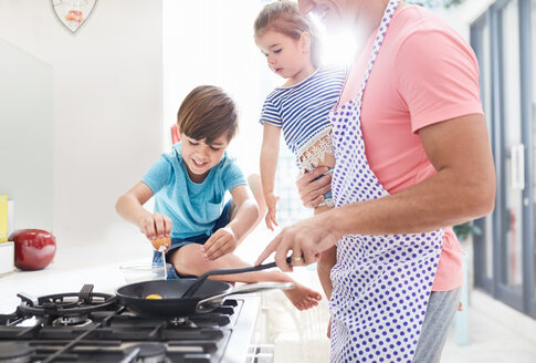 Vater kocht Frühstück am Herd mit Tochter und Sohn - CAIF09383