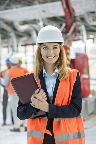 Porträt einer lächelnden Ingenieurin auf einer Baustelle, lizenzfreies Stockfoto