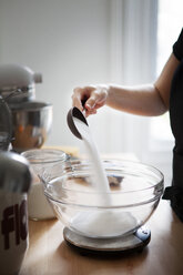 Ausgeschnittenes Bild einer Frau, die Mehl in eine Schüssel auf einer Küchenwaage gießt - CAVF04435
