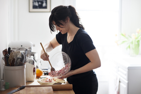 Woman pouring food from bowl in container for preparing pie stock photo