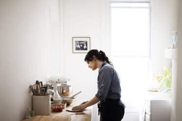 Seitenansicht einer Frau bei der Zubereitung von Essen zu Hause - CAVF04468