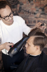 Friseur föhnt die Haare eines Mannes im Salon - CAVF04493