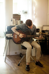 Man practicing guitar at home - CAVF04506