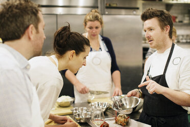 Chef showing ingredient to students at commercial kitchen - CAVF04520