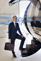 Porträt eines Geschäftsmannes, der auf der Treppe eines Flugzeugs steht - CAVF04557