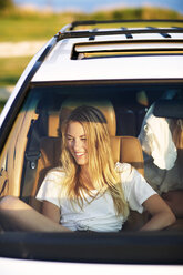 Smiling woman looking away while sitting in car - CAVF04643