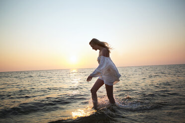 Side view of woman walking in water at beach against clear sky - CAVF04648