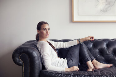 Porträt einer Frau, die zu Hause auf dem Sofa sitzt - CAVF04669