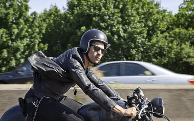 Confident man riding motorcycle on road - CAVF04690