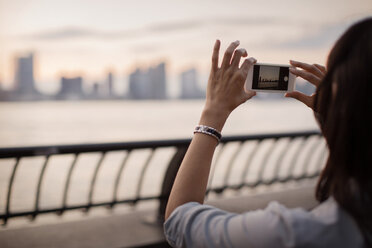 Frau fotografiert die Skyline der Stadt bei Sonnenuntergang - CAVF04732