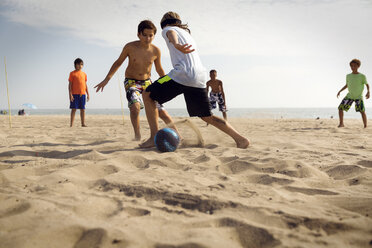 Freunde spielen Fußball am Strand gegen das Meer - CAVF04828