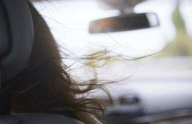 Wehende Haare einer Frau im Auto - CAIF09410