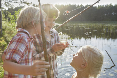 Brüder und Schwester angeln am sonnigen Teich - CAIF09413