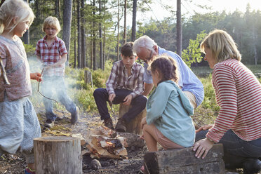 Grandparents and grandchildren enjoying campfire at lakeside - CAIF09421