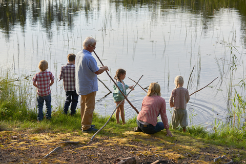 Großeltern und Enkelkinder beim Angeln am See, lizenzfreies Stockfoto