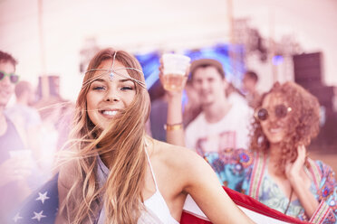 Portrait smiling young woman with American flag at music festival - CAIF09433