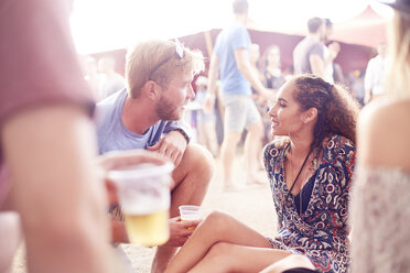 Junges Paar trinkt Bier und unterhält sich auf einem Musikfestival - CAIF09436