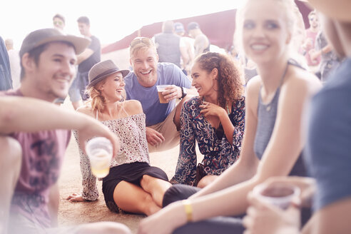 Junge Freunde, die auf einem Musikfestival Bier trinken und sich unterhalten - CAIF09444