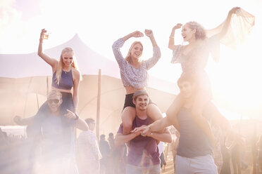 Young men carrying playful women on shoulders at music festival - CAIF09452