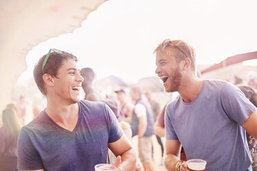 Junge Männer trinken und lachen auf einem Musikfestival - CAIF09457