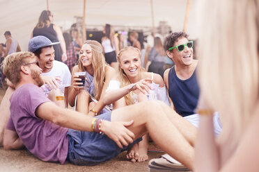 Junge Freunde beim Trinken und Reden auf einem Musikfestival - CAIF09458