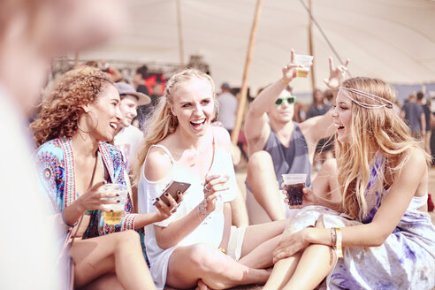 Junge Frauen beim Trinken auf einem sonnigen Musikfestival - CAIF09459
