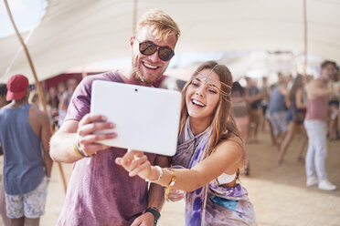 Young couple taking selfie with digital tablet at music festival - CAIF09462