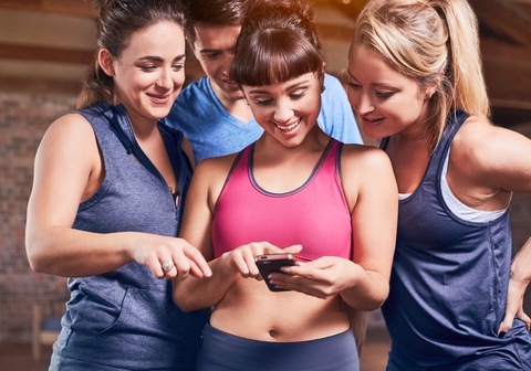 Junge Frau und Mann in Sportkleidung schreiben SMS mit Handy, lizenzfreies Stockfoto