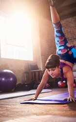 Junge Frau übt Skorpion Hund Yoga-Pose im Fitness-Studio - CAIF09520