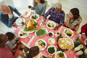 Draufsicht auf eine multiethnische Mehrgenerationenfamilie beim Weihnachtsessen am Tisch - CAIF09573