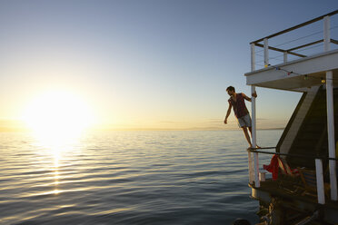 Mann lehnt auf Sommer Hausboot Reling über Sonnenuntergang Meer - CAIF09576