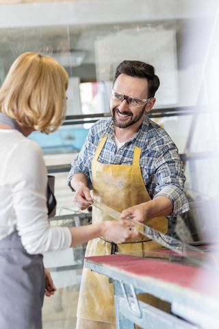 Lächelnde Glasmalerei-Künstler im Gespräch im Atelier, lizenzfreies Stockfoto