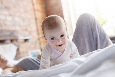 Porträt lächelnd Baby Mädchen auf dem Bett mit Mutter - CAIF09663